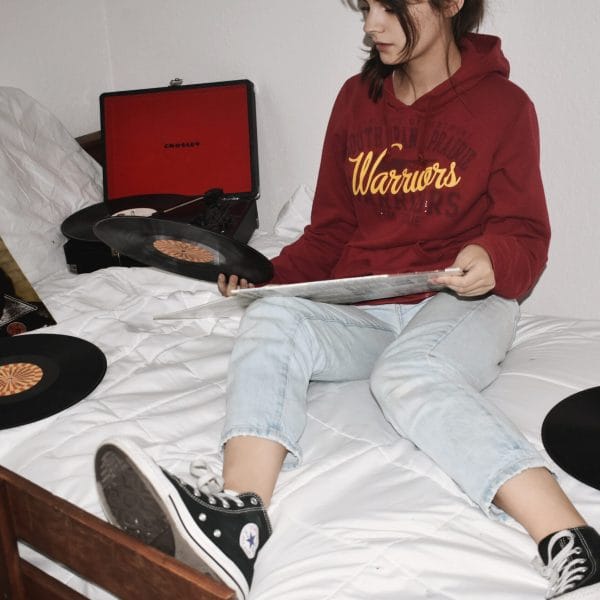 Teen on bed with records and record player