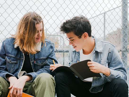 two teens looking at journal