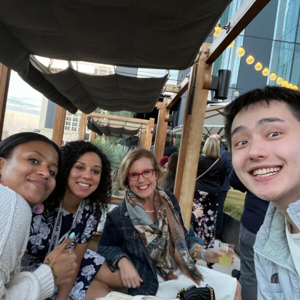 selfie of a group of four people looking at the camera over a table of food 